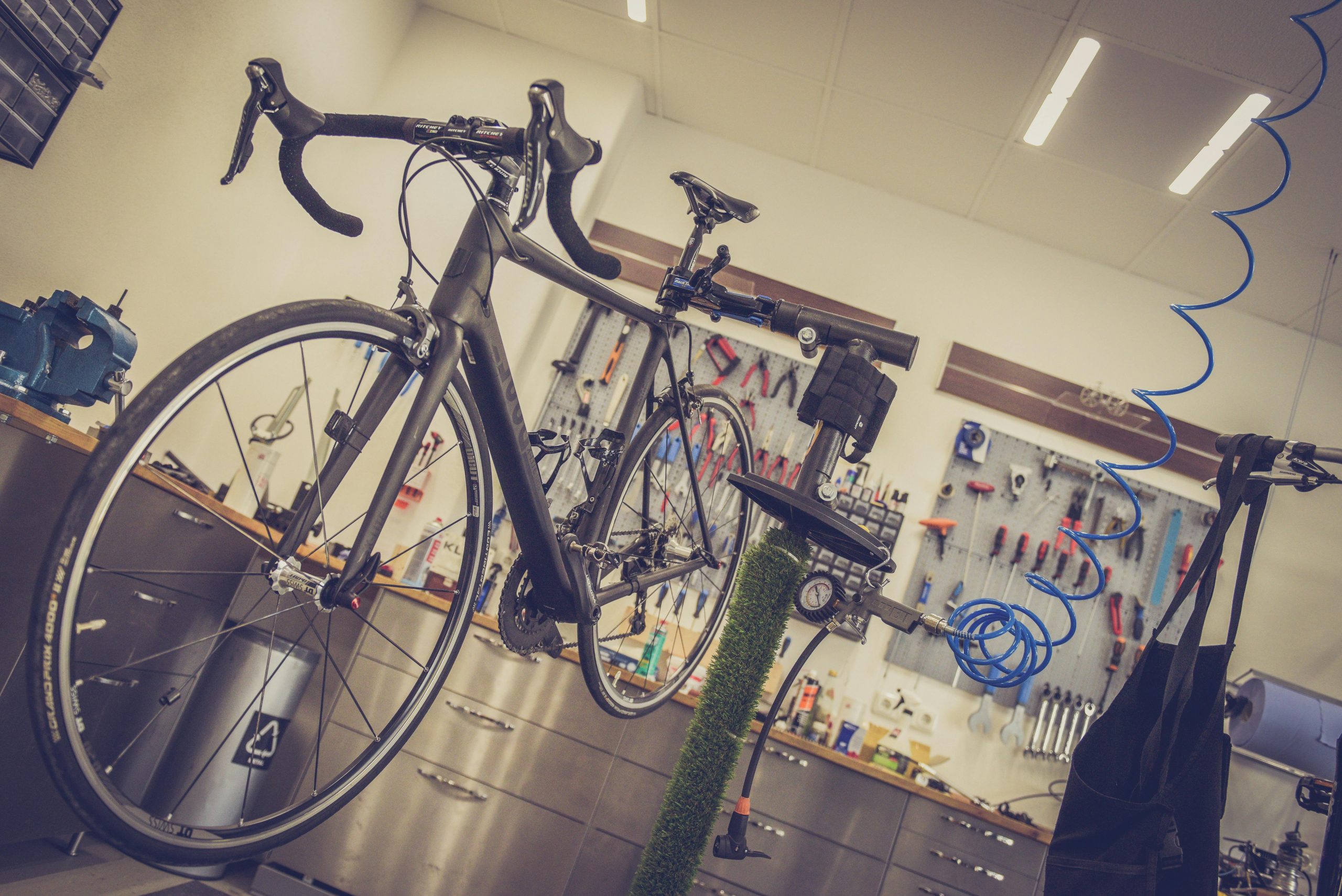 Home Detailed view of a bicycle being repaired in a modern workshop with tools and equipment.